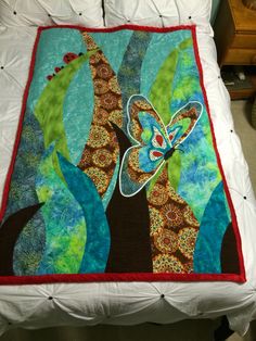 a quilted bed with a butterfly on the tree and blue sky in the background