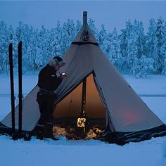 a man standing next to a tent in the snow