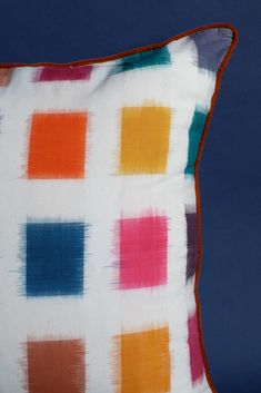 a multicolored pillow sitting on top of a blue surface with an orange border