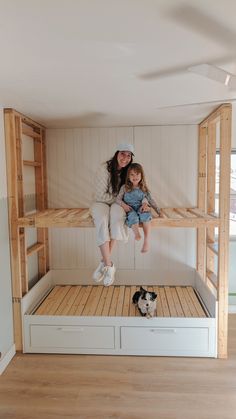 a woman and child sitting on top of a bunk bed