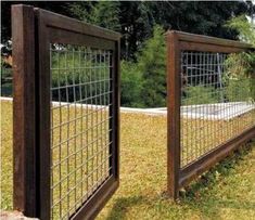 the fence is made of metal wire and has wooden posts on each side, along with grass