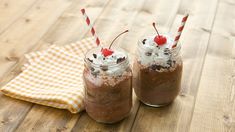 two mason jars filled with chocolate milkshakes and topped with whipped cream and cherries