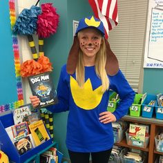 a girl in a blue shirt and hat holding a book