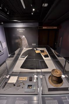 there are many artifacts on display in this museum case, including an old hat and other items