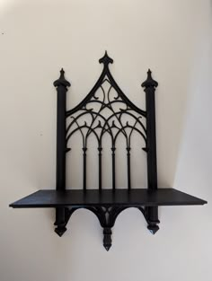 an iron shelf with two black shelves on each side and one white wall behind it