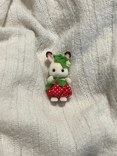 a white teddy bear with a green hat and red dress on it's lap