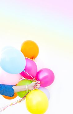 a woman is holding many balloons in her hand