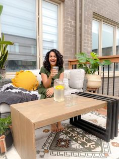 a woman sitting on a couch holding a glass in her hand and smiling at the camera