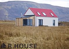 a house in the middle of a field with mountains in the background