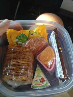 a plastic container filled with lots of food and some kind of snacks on top of it