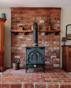 an old fashioned stove in a living room with red brick walls and wooden shelves on either side