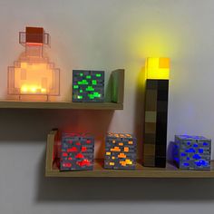 several lit up cubes are sitting on the shelf next to each other in front of a candle