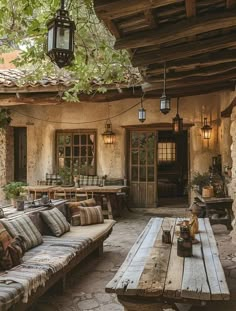 an outdoor living area with couches, tables and lights hanging from the ceiling above