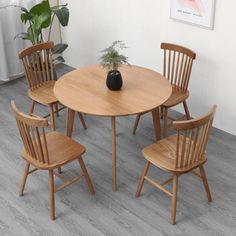 a wooden table with four chairs and a plant on top of it in an empty room