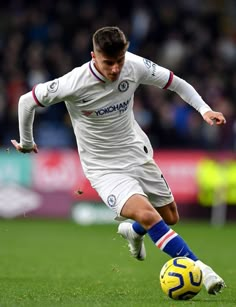 a man kicking a soccer ball on top of a field