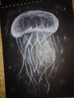 a chalk drawing of a jellyfish on a black paper with white writing underneath it