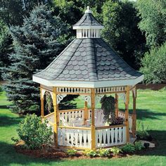 a wooden gazebo in the middle of a grassy area