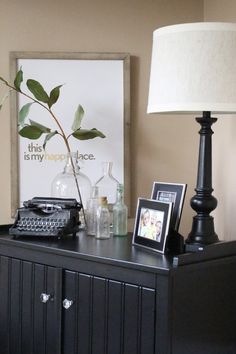 a table with a lamp, phone and pictures on it next to a framed photograph