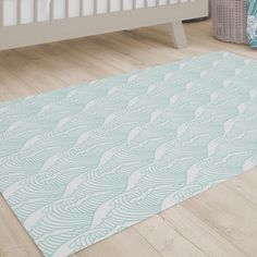 a baby's room with a white crib and blue rug on the floor