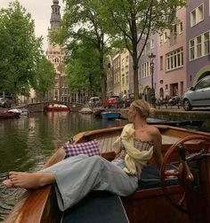 a woman sitting on the back of a boat in a canal