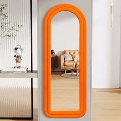 an orange mirror sitting on top of a wooden floor