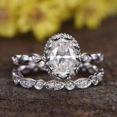 a close up view of a diamond ring on a wooden surface with flowers in the background