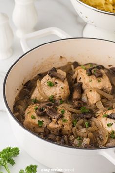 a pan filled with chicken and mushrooms on top of a counter next to pasta shells