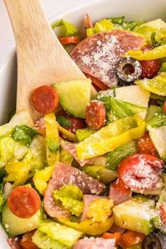 a salad with tomatoes, cucumbers, and other vegetables in a white bowl