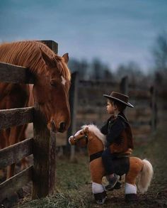 a little boy that is standing next to a horse