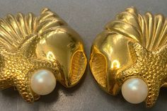 STUNNING vintage 1980's clip on earrings featuring a beautiful sea inspired design. A gorgeous faux white pearl set under the starfish, next to it a beautiful tall shell and with a beautiful clam set on the back. The detail is amazing! Surrounded in a lavish ornate gold plated metal. The perfect pair of earrings for any beach/sea lover! Measurements: The length and width is 2.7cm Condition: In ABOVE excellent vintage condition, The clips are secure. Please look at the photos as they are truly re Sea Lover, Sea Inspired, Beautiful Sea, Pearl Set, Vintage Beach, Vintage Jewellery, White Pearl, Starfish, Pearl White