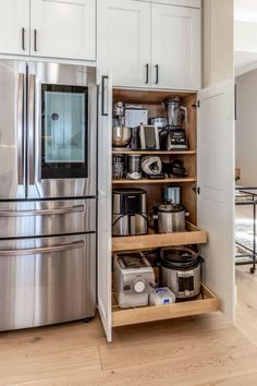 an organized kitchen with stainless steel appliances and white cabinetry, along with wooden flooring