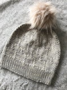 a knitted hat with a pom - pom sitting on top of it