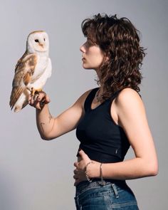 a woman holding an owl in her right hand