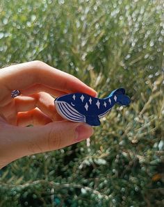 a hand holding a small blue and white fish ornament in it's palm