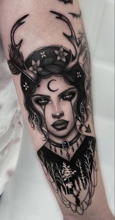 a woman with horns and feathers on her head is shown in this black and white tattoo