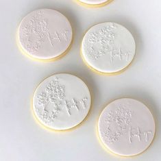 four decorated cookies sitting on top of a white table next to each other with writing on them