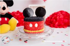 a mickey mouse cake is sitting on a glass plate next to a red and yellow minnie mouse