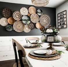 a dining room table set with plates and place settings on the wall above it is an arrangement of woven baskets