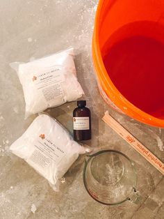 an orange bucket filled with liquid next to other items