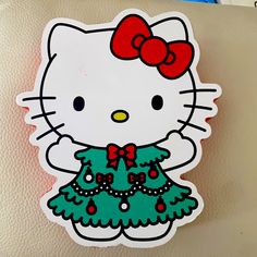 a hello kitty sticker with a christmas tree on it's bottom and red bow at the top