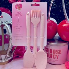 three pink kitchen utensils are sitting on a table next to some other items