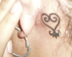 a close up of a person's ear with a heart tattoo on the side