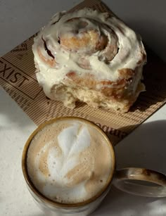 a cup of coffee sitting next to a pastry