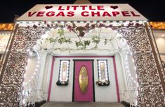 the entrance to a las vegas chapel decorated with flowers and lights at night time,