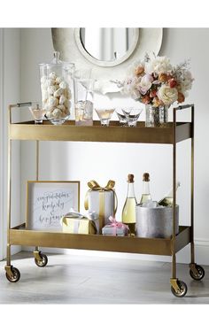 a gold bar cart with drinks and flowers on it