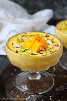 two glasses filled with dessert sitting on top of a table