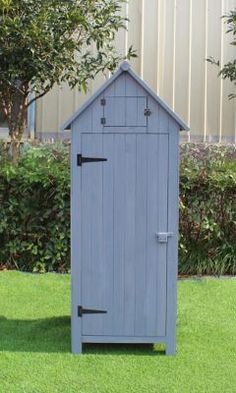 a small blue shed sitting in the middle of a yard next to a white fence