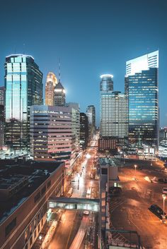 the city skyline is lit up at night, with skyscrapers in the foreground