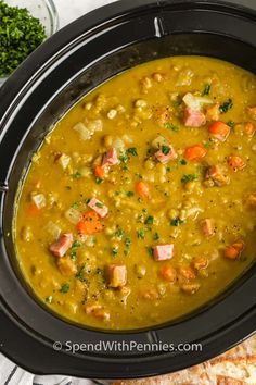 a black crock pot filled with soup next to some pita bread and parsley