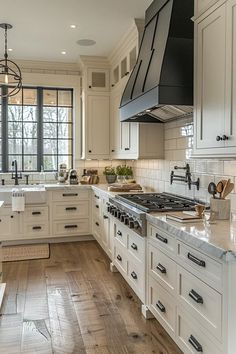 a large kitchen with white cabinets and wood floors